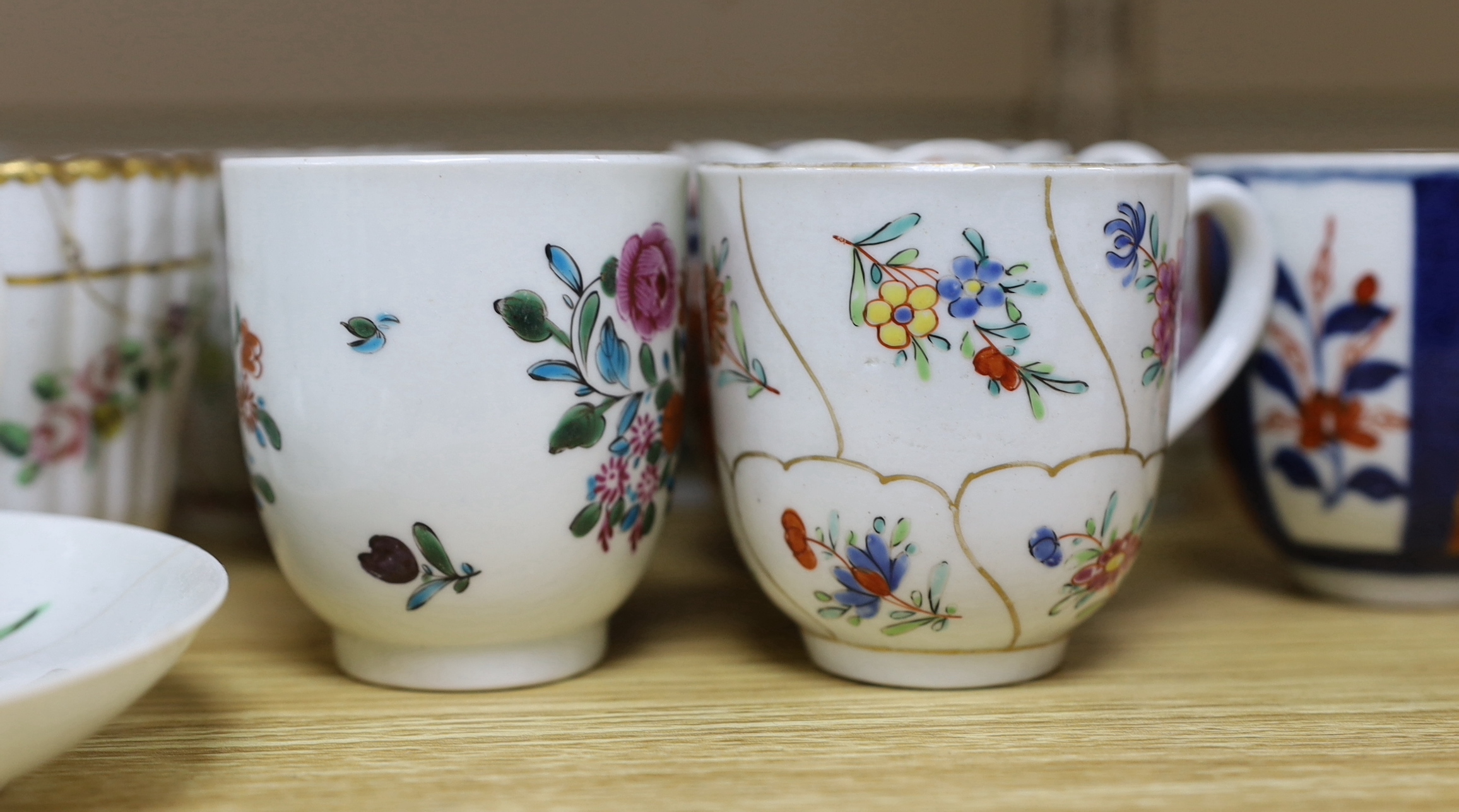 A collection of late 18th century Worcester and Lowestoft coffee cups and a saucer, many hand painted with flowers, the largest 12cm in diameter
